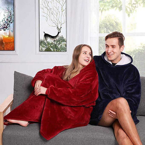 Couple wearing their snuggie huggle slanket, siting on a couch and lounging in living room 