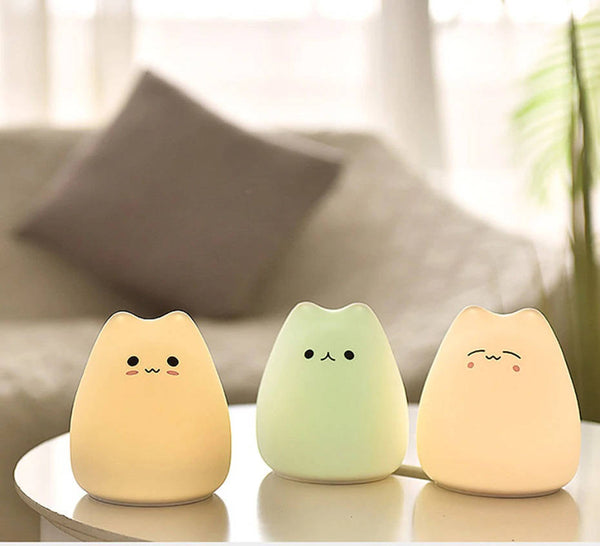 Squishy the cutest cat night light table lamp with three different hues with a bokeh background